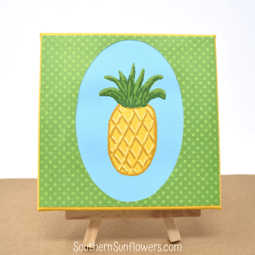 Completed painted pineapple craft on an easel.