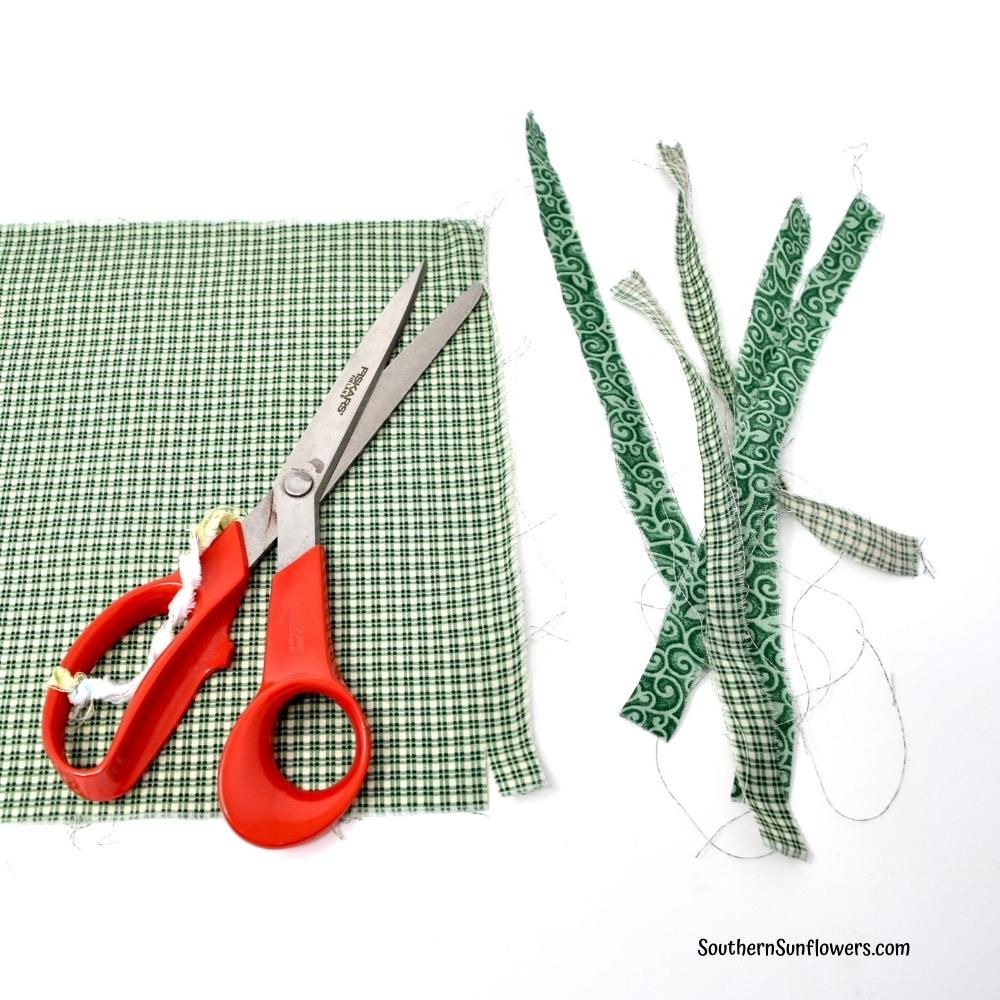 green plaid fabric snipped and then pulled apart to make strips 