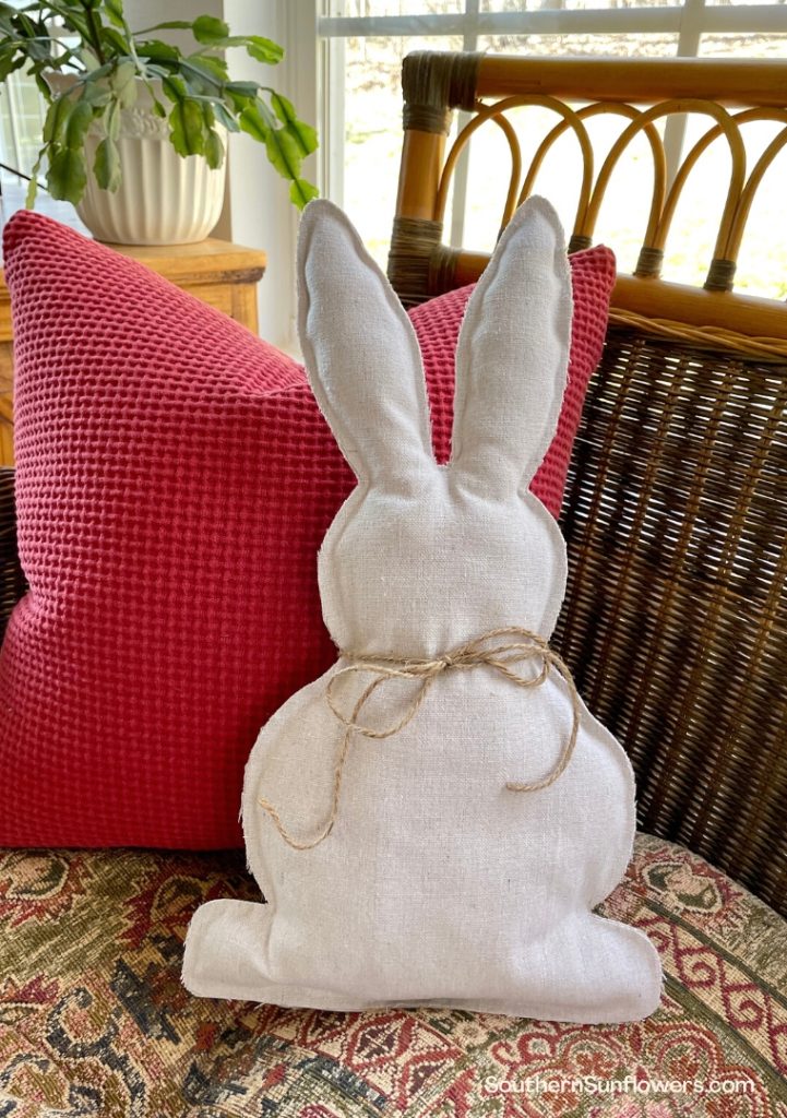 completed no sew drop cloth bunny pillow displayed on a couch